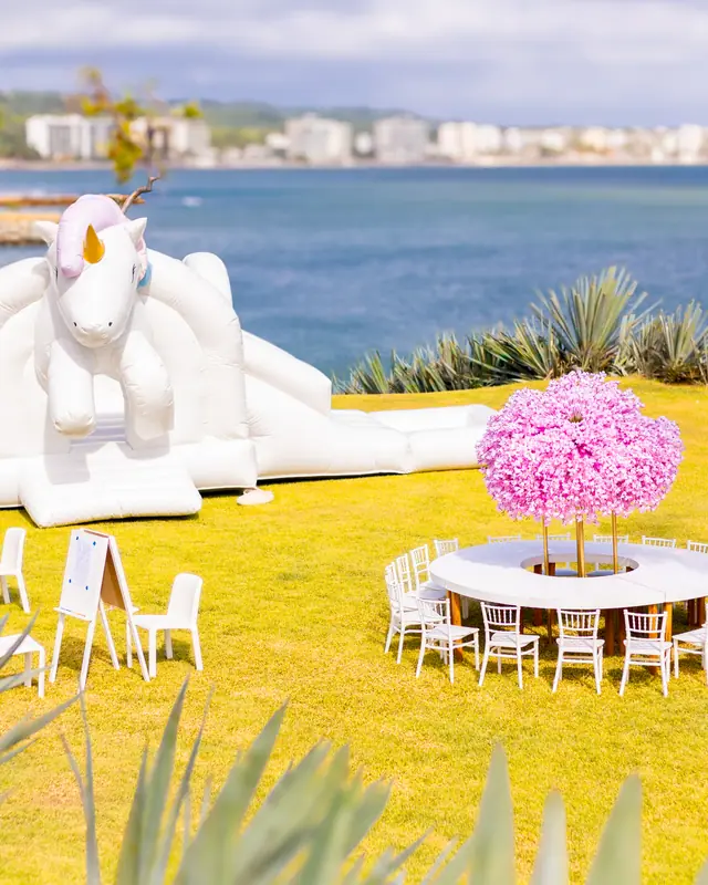 Inflable de unicornio y mesa redonda con flor lila frente al mar