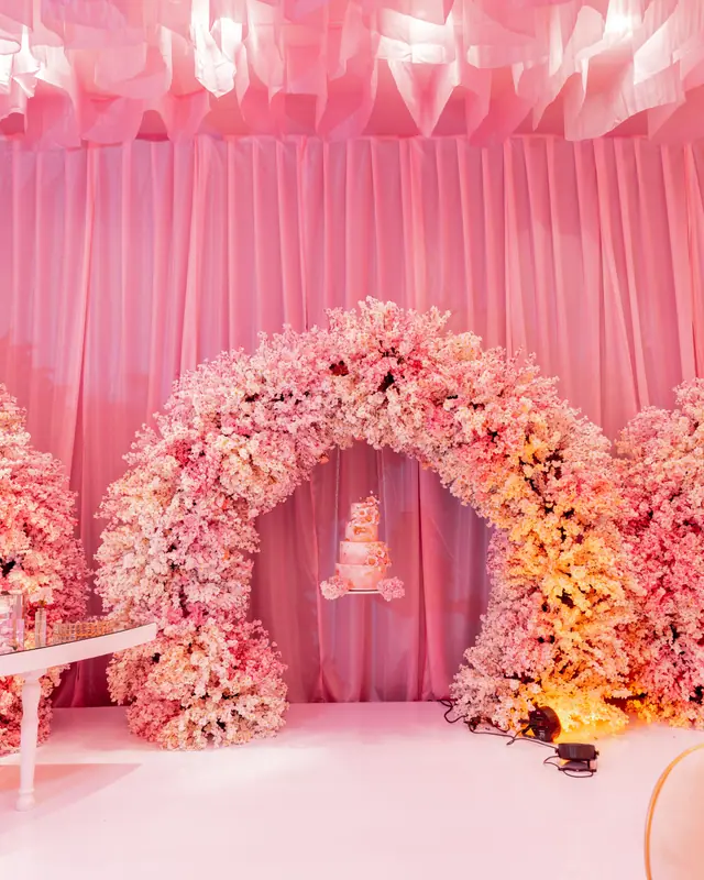 Arco de flor en tonos blush con el pastel suspendido al centro