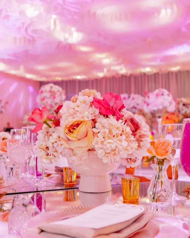 Plato base con servilleta, menú y centro de flores en tonos rosa