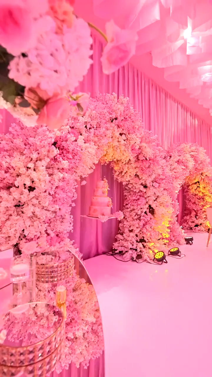 Recorrido por un salón entelado en rosa hacia los arcos de flor